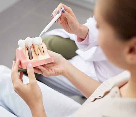 a patient holding a model of a dental implant