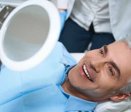 a patient checking his smile with a mirror