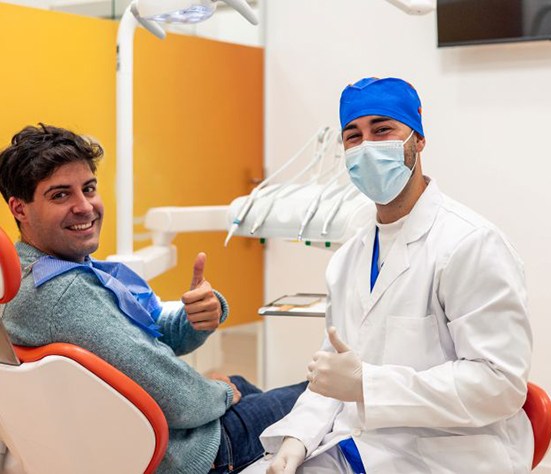 Dentist and patient making thumbs-up gesture