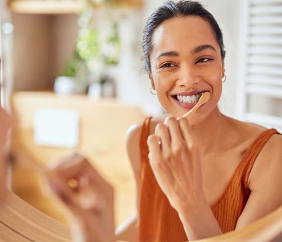 Woman brushing her teeth in front of bathroom mirror