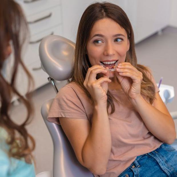 Happy dental patient holding clear aligner