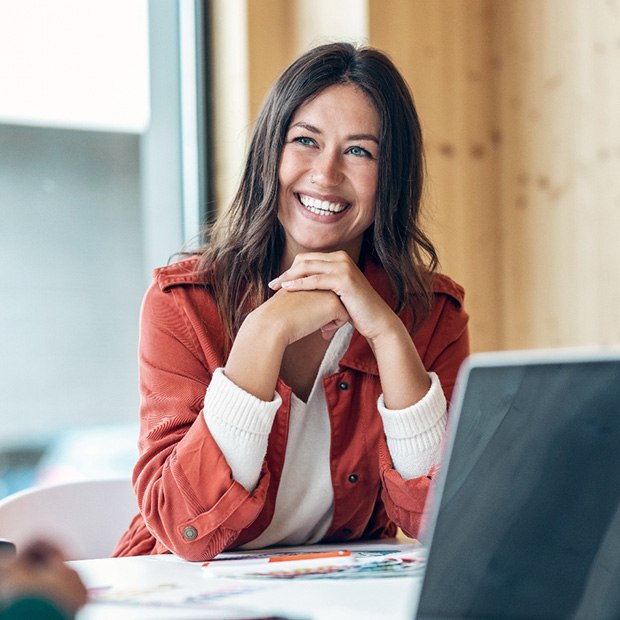 Smiling, confident woman sitting at desk in business setting