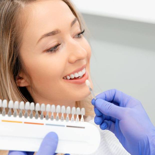 Dentist holding shade guide next to patient’s teeth