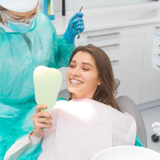 Happy dental patient looking at her smile in mirror
