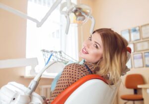 Young woman in dental treatment chair, looking over her shoulder 